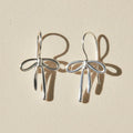 Silver bow tie ribbon drop earrings with dangling charms