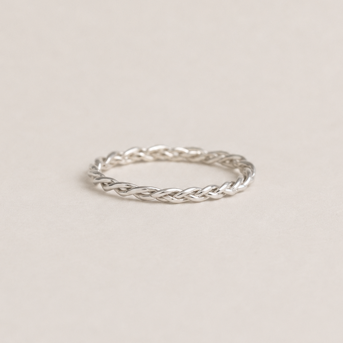Silver braided ring on a light beige background