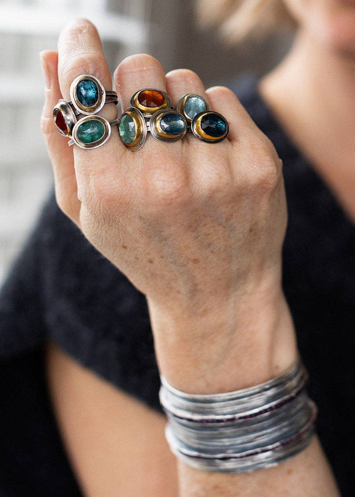 Silver-tone ring with teal oval center stone and gold-toned bezel, stackable style
