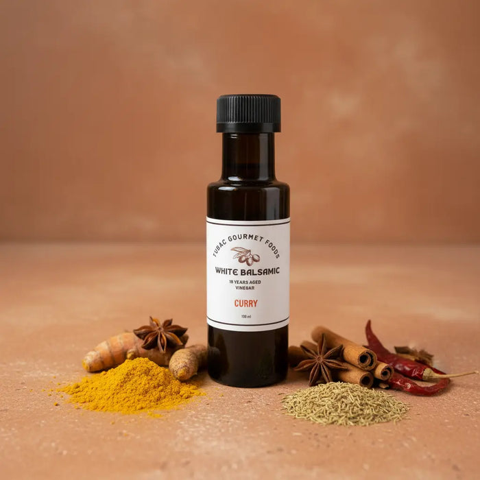 Curry White Balsamic Vinegar bottle with curry spices on terracotta surface