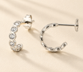 Silver-tone huggie hoop earrings with round clear stones, hinged closure