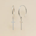 Silver hoop earrings with small cross charms dangling from hinged loops