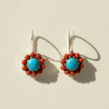 Pair of earrings with blue center and red accents on a white background