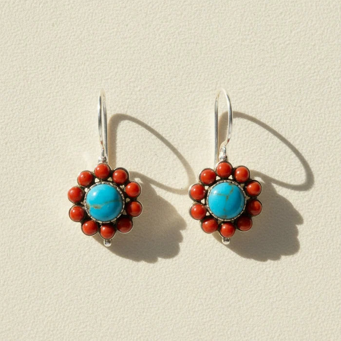 Pair of earrings with blue center and red accents on a white background