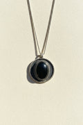 Shield pendant necklace with dark oval cabochon and textured outer ring