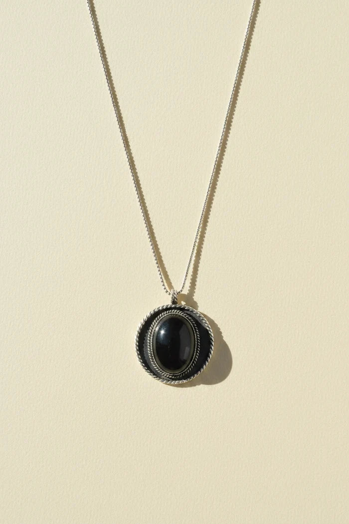 Shield pendant necklace with dark oval cabochon in textured round bezel