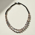 Double-strand pearl necklace with black cord on a white background