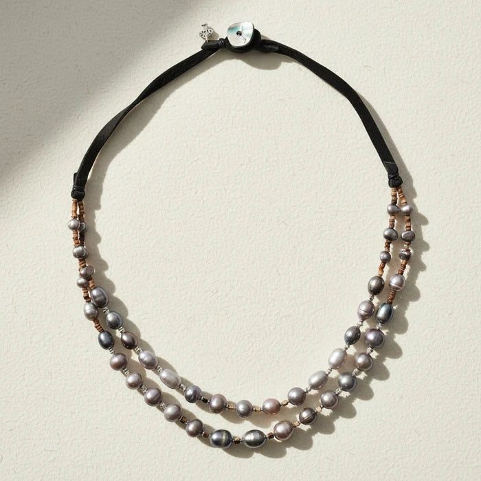 Double-strand pearl necklace with black cord on a white background