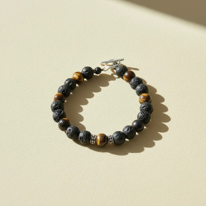 Beaded talisman bracelet with dark stone beads, brown-gold accents, and silver clasp