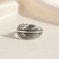 Silver feather-shaped ring on a white background