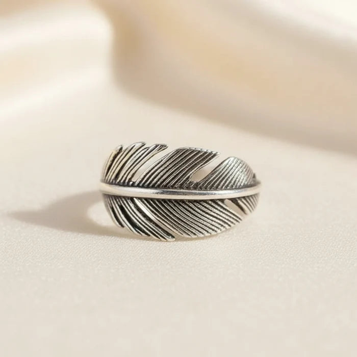 Silver feather-shaped ring on a white background