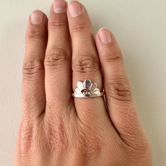 Silver flower crown ring with white petals and gold bead center on slim band
