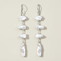 Pearl drop earrings on a beige background