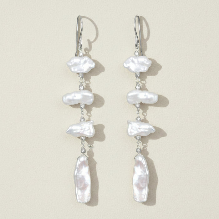 Pearl drop earrings on a beige background