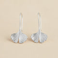 Silver ginkgo leaf drop earrings with curved leaf shapes and narrow hoop hooks.