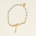 Gold bracelet with pearl beads and a heart charm on a white background