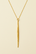 Gold necklace with a long, thin pendant on a white background