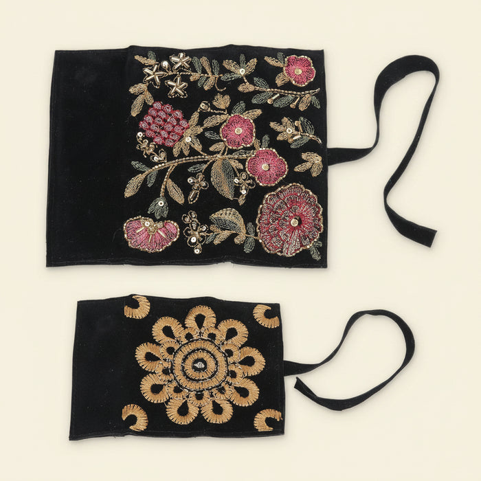 Black jewelry roll pouch with ornate gold and pink floral embroidery; tied string closure.