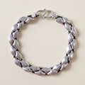 Silver bracelet with leaf-like design on a white background