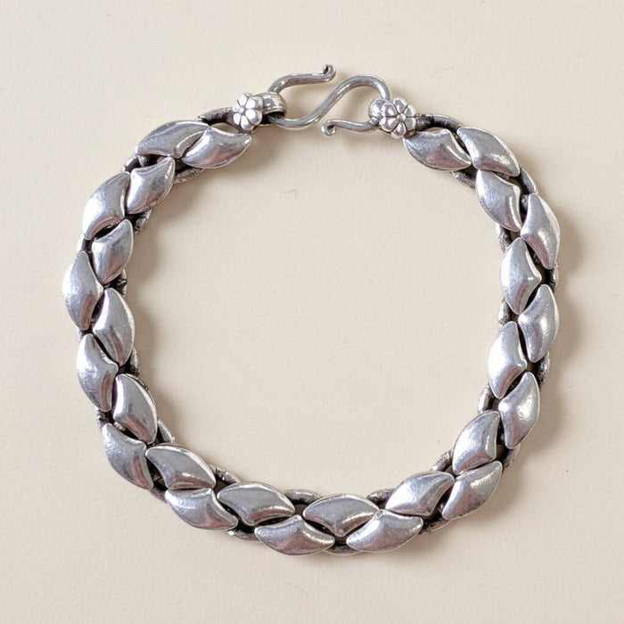Silver bracelet with leaf-like design on a white background