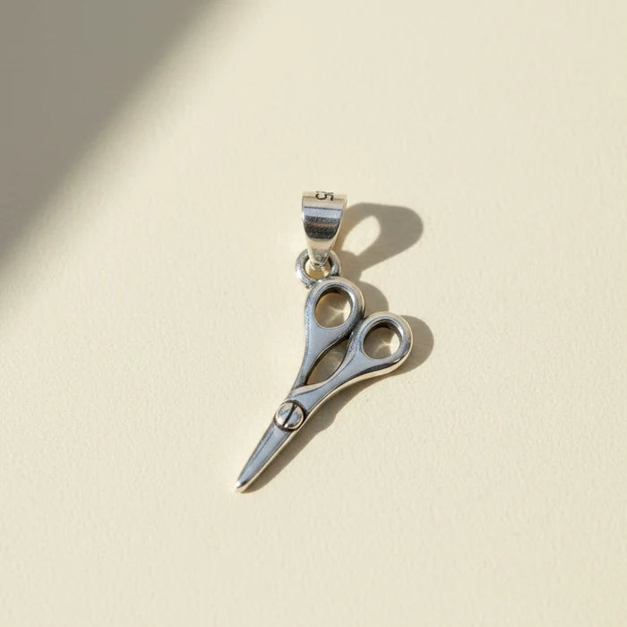 Scissors-style pendant with circular accents and small trim bail