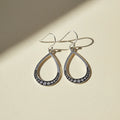 Large silver teardrop beaded earrings with dark bead border and hoop hooks