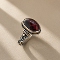 Oval garnet cabochon ring, engraved silver shoulders around deep red stone