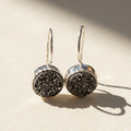 Black druzy round dangle earrings with silver-tone round settings and hoop hooks