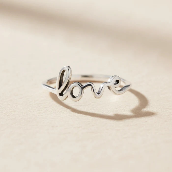 Silver-toned Love script ring with raised cursive lettering and heart dot