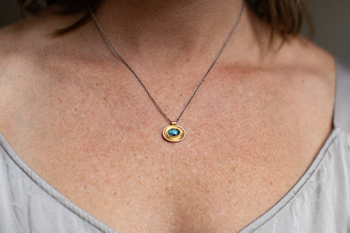 Oval necklace with mixed metal chain and blue oval glass pendant