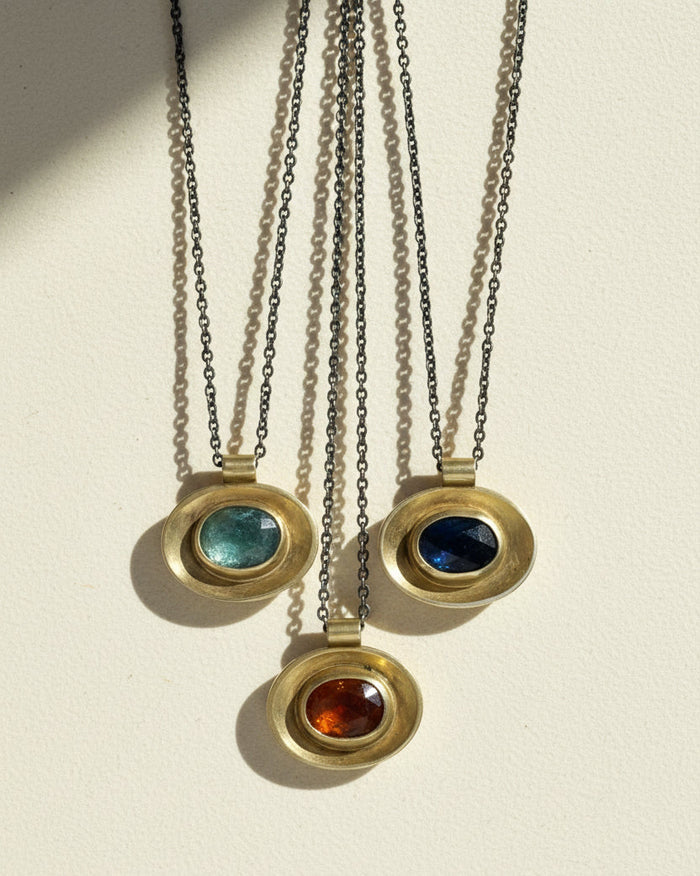 Oval pendant set on silver chains: green, blue, and red stone centers
