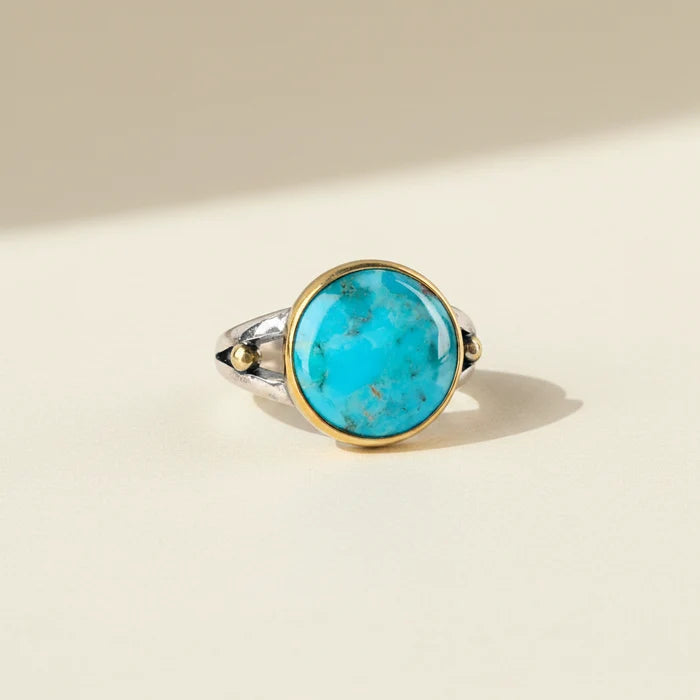Turquoise oval gemstone ring with gold bezel and silver band, small side stones