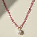 Pink beaded choker necklace with a round white pearl pendant on a gold bail