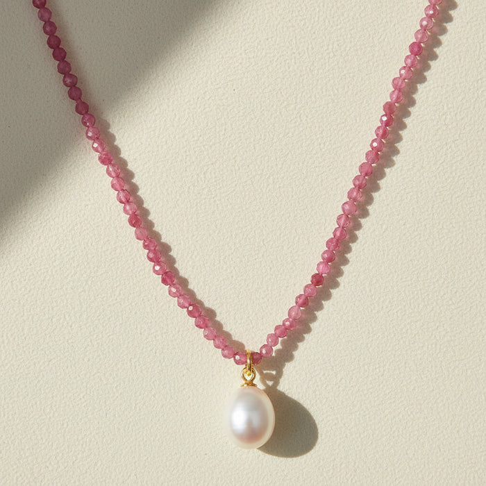 Pink beaded choker necklace with a round white pearl pendant on a gold bail