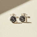 Silver-tone rose swirl stud earrings with black enamel center