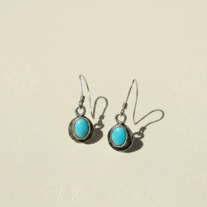 Turquoise oval drop earrings with dark metal bezel and fishhook backs