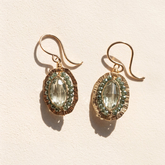 Gold-tone oval drop earrings with green faceted center stone and beaded halo.