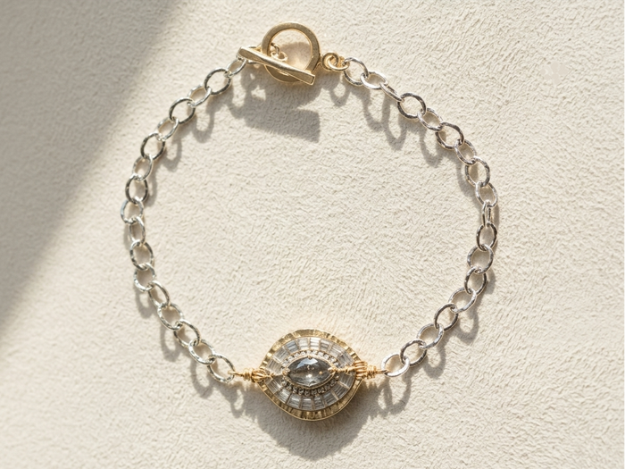 Silvertone chain bracelet with round medallion center in gold and dark details