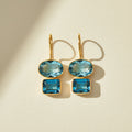 Gold-tone double drop earrings with oval and square teal-blue gemstones