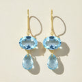 Gold-tone ear wire earrings with blue oval gemstone and blue teardrop dangle