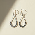 Small silver teardrop beaded earrings with textured border and hanging hook