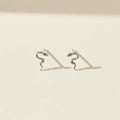 Pair of silver snake-shaped earrings on a beige background