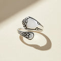 Silver spoon-shaped ring with engraved floral swirls and curved band