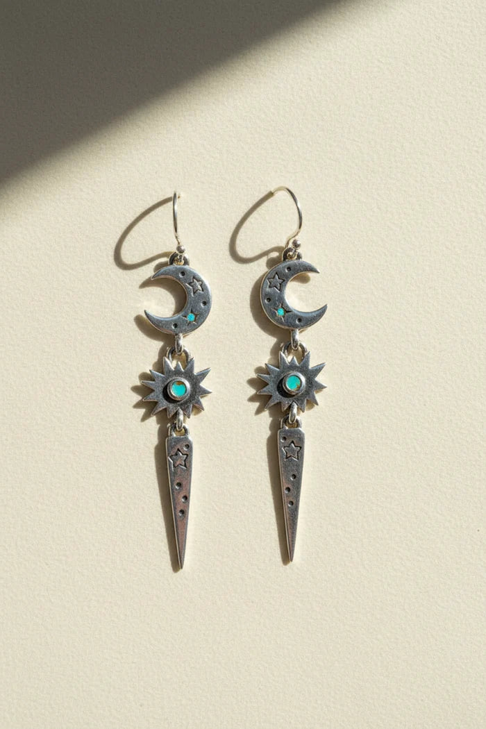 Stardust earrings with dangling crescent moons, blue starburst gems, and long teardrop charms