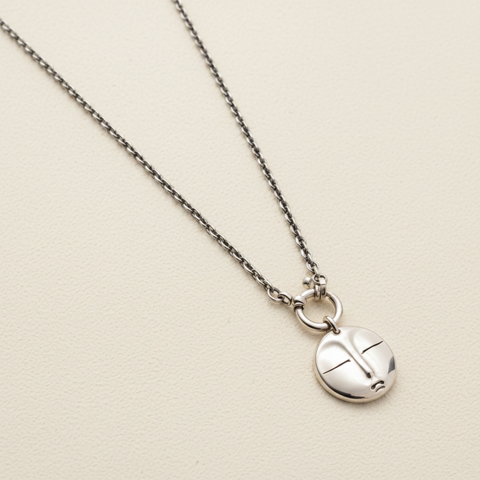 Silver necklace with a round pendant on a white background