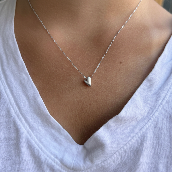Heart pendant necklace with small silver heart charm, worn on collarbone