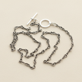 Silver chain necklace on a white stand with a white background