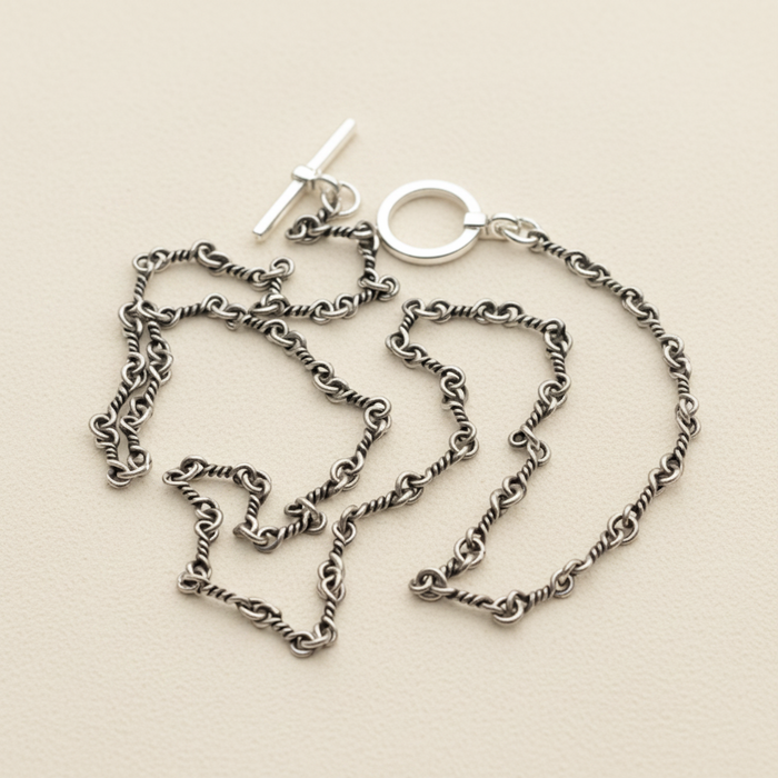 Silver chain necklace on a white stand with a white background