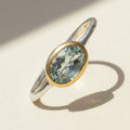 Two-tone aquamarine ring with oval blue-green stone and gold bezel