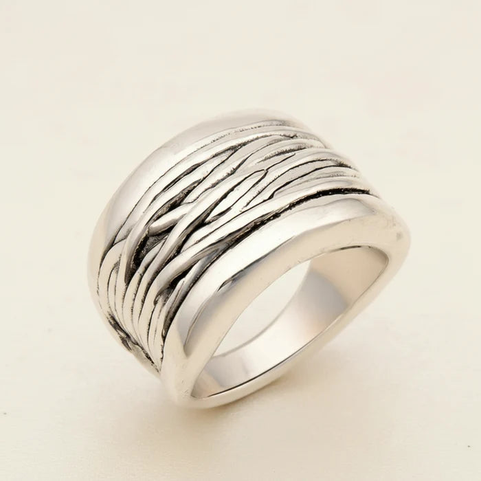 Silver ring with textured design on a white background